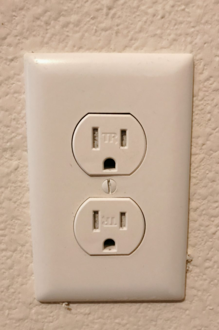 アメリカの家の壁のコンセント（outlet）。2つの差し込み口に、縦の穴2つと丸い穴1つ