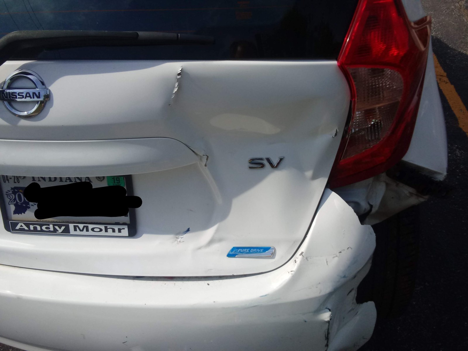 後ろからぶつけられてへこんだ白い車のバンパー