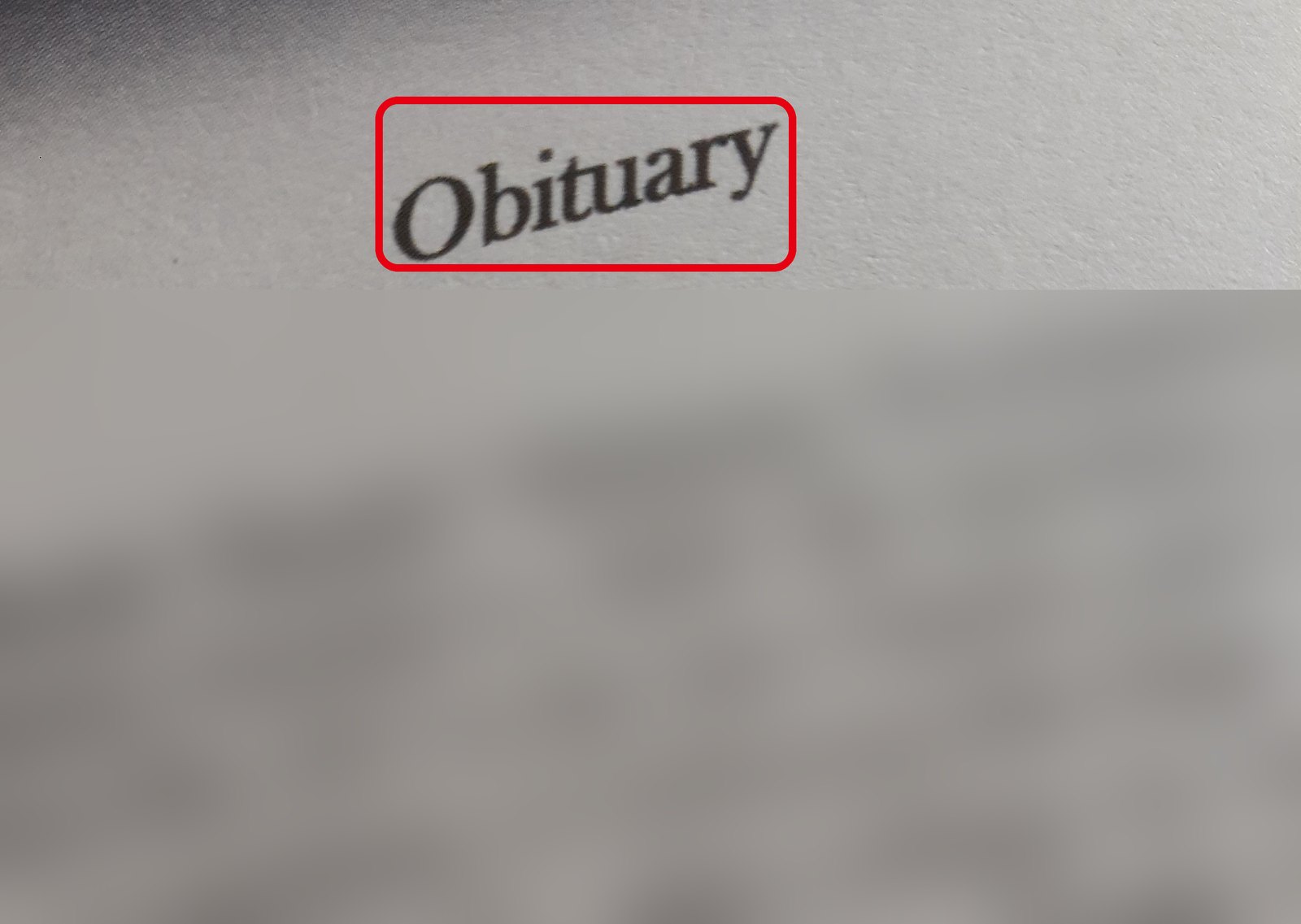 「Obituary」と書かれた追悼記事の紙