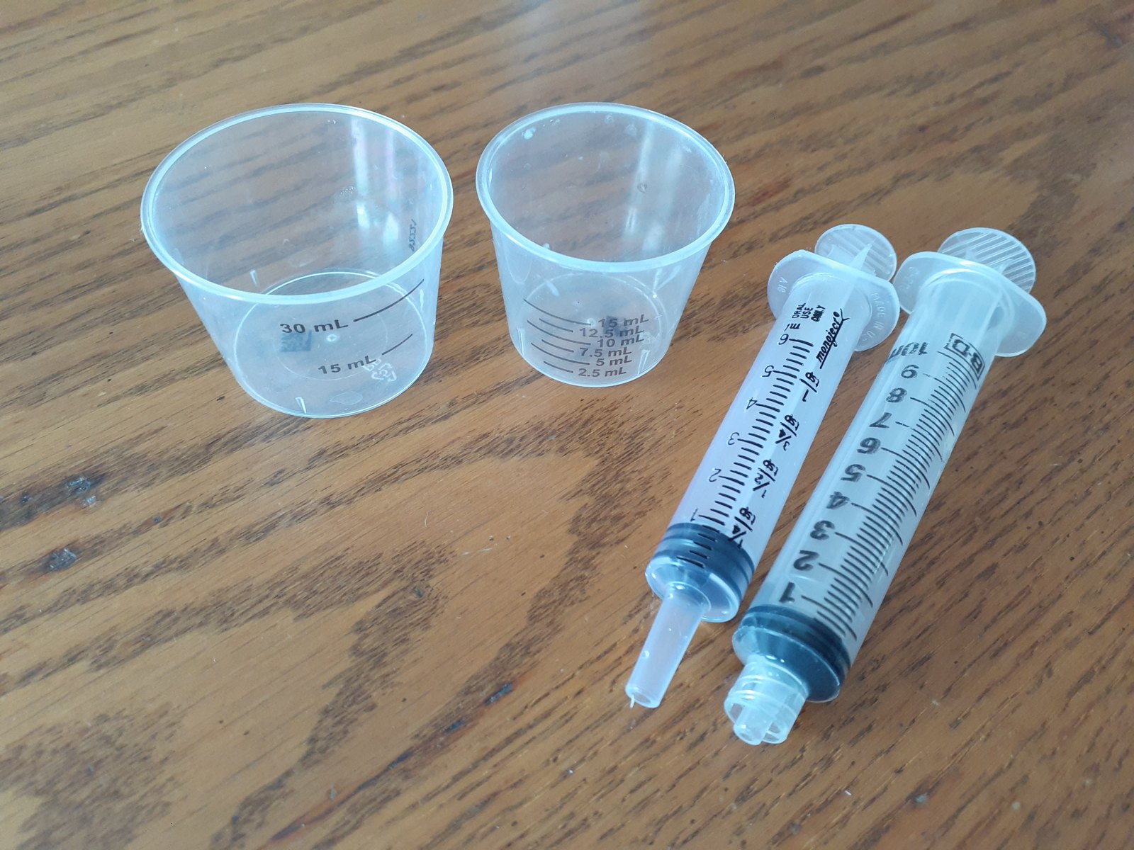 子どもの飲み薬を量る計量カップとシリンジ(mL の目盛り)