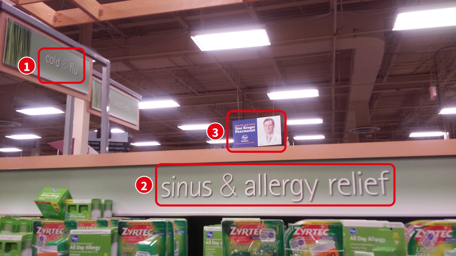 スーパーの薬売り場の看板「cold & flu」「sinus & allergy relief」と、薬剤師の紹介ポスター
