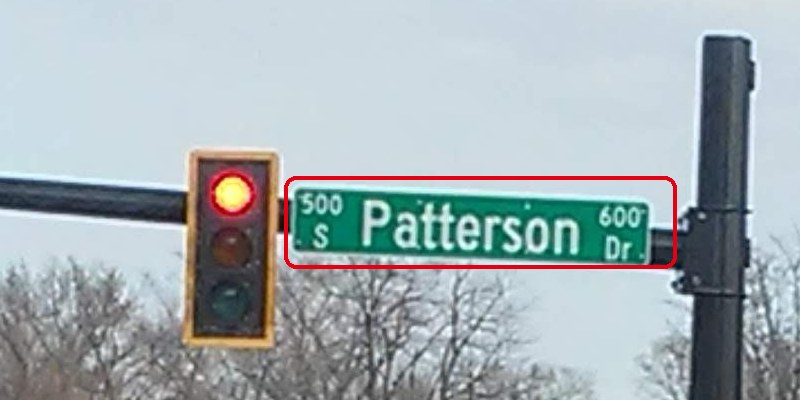 信号の横に付いた緑の通りの名前の標識「500 S Patterson 600 Dr」